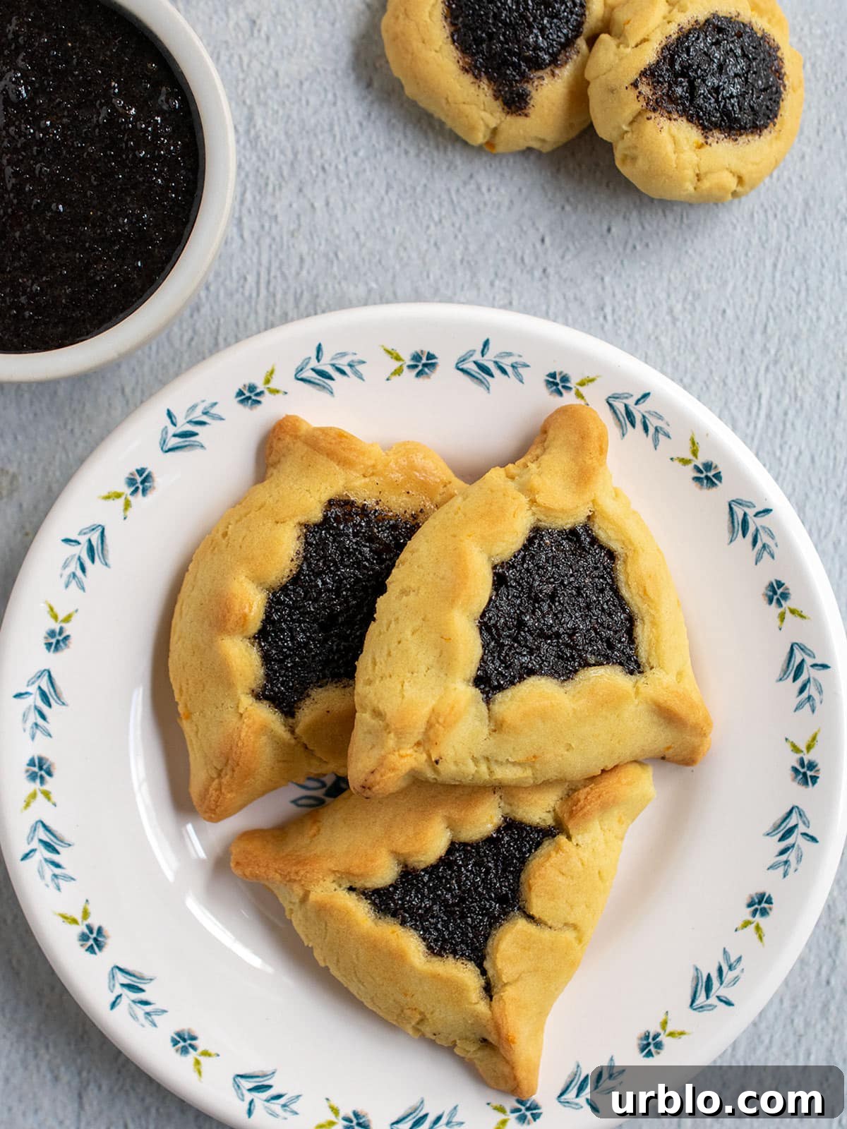 Hamantaschen filled with poppy seed filling and a bowl of poppy seed filling.