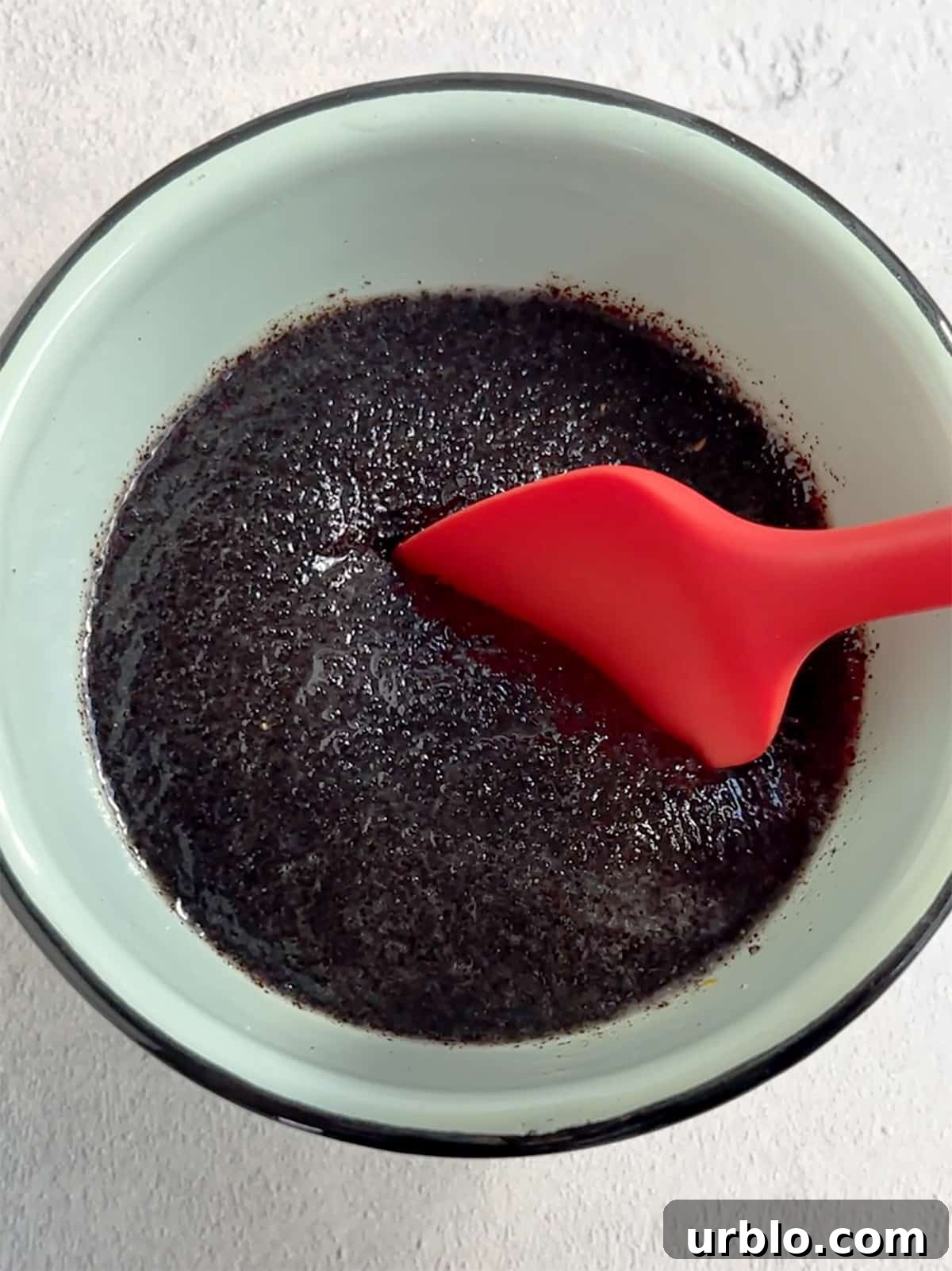 Poppy seed filling in bowl with a red spatula.