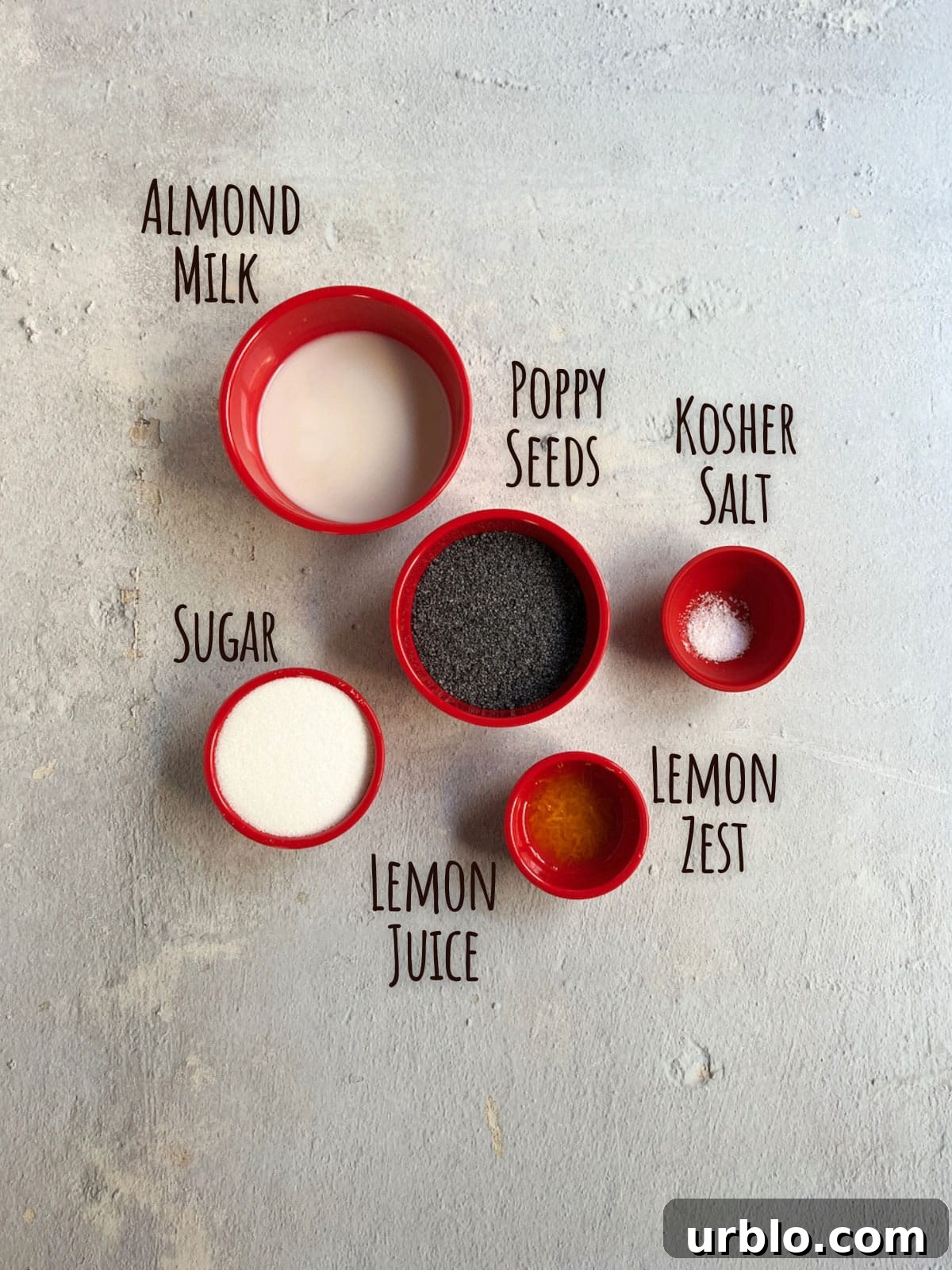 Ingredient shot showing almond milk, poppy seeds, lemon juice and zest, sugar and salt.