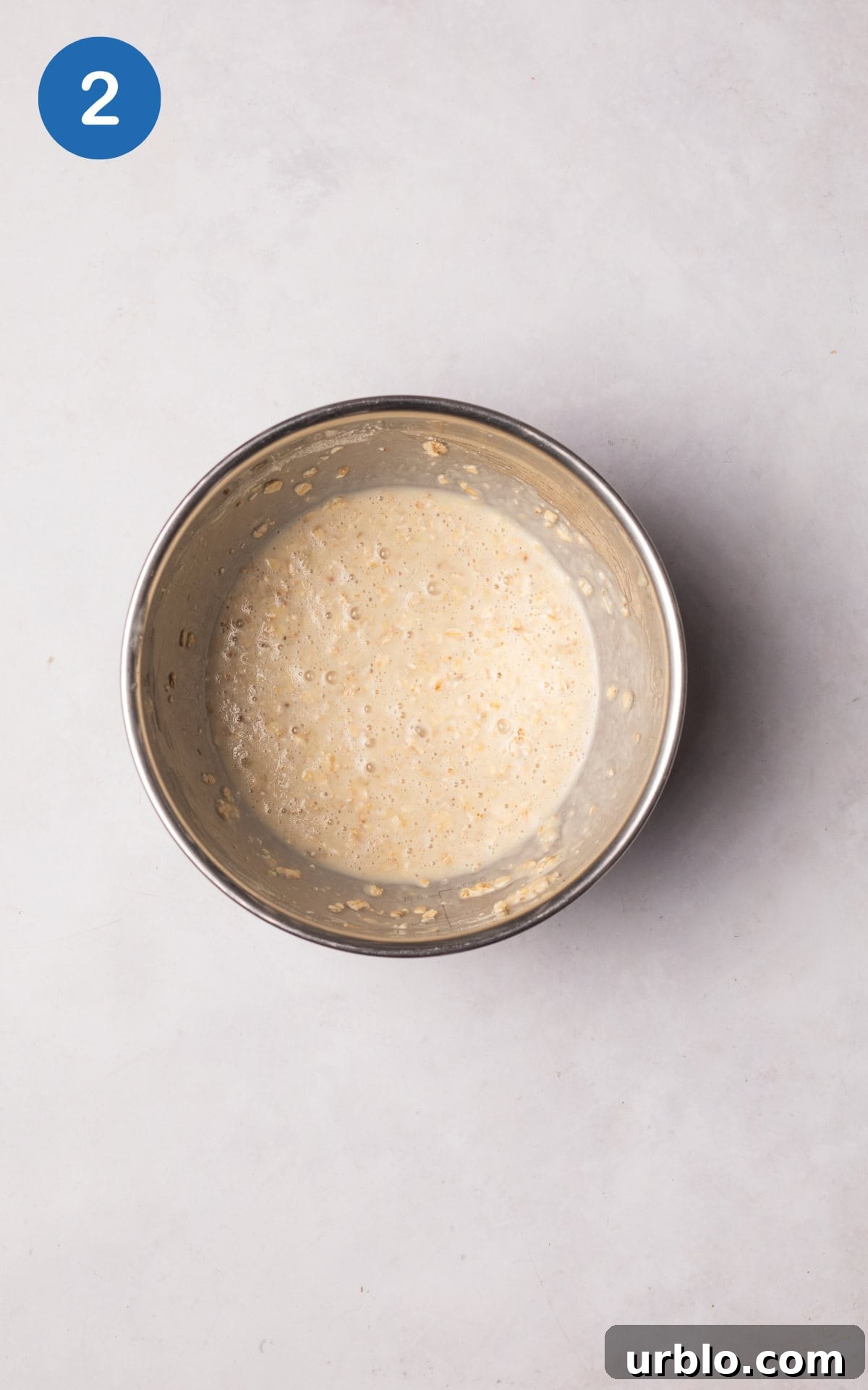 Combining  protein powder, baking powder, milk, and oats with banana in a bowl.