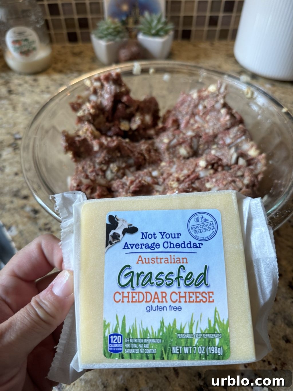 A package of Australian grassfed cheddar in front of a glass bowl of ground beef mixture.