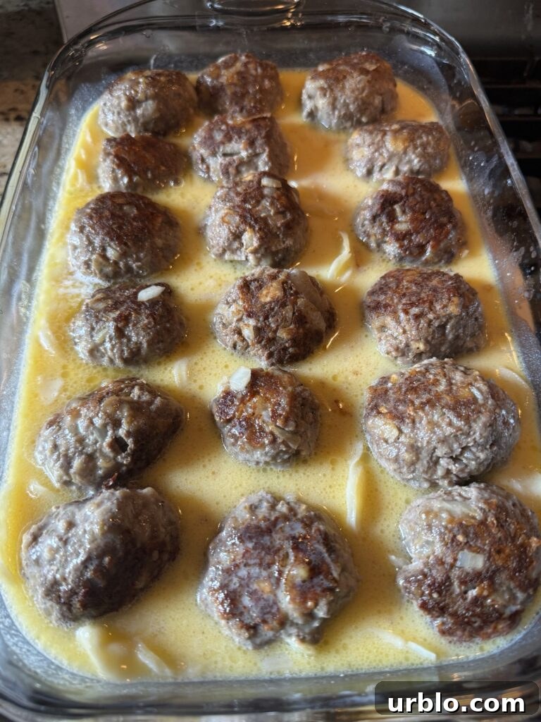 Meatballs in Au Gratin Potato mixture in a baking dish.