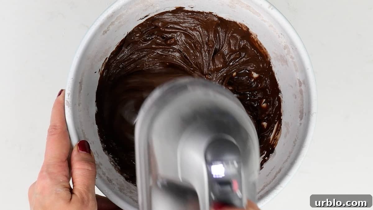 making chocolate frosting in a bowl with a hand mixer