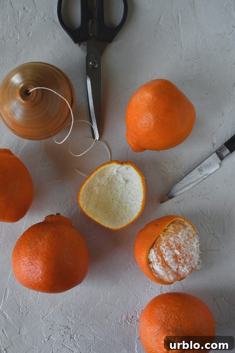 Oranges on a table, one has had its peel removed in one large piece.