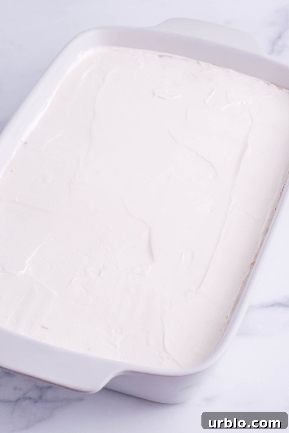 smoothed whipped cream in a 9x13 baking dish on table 
