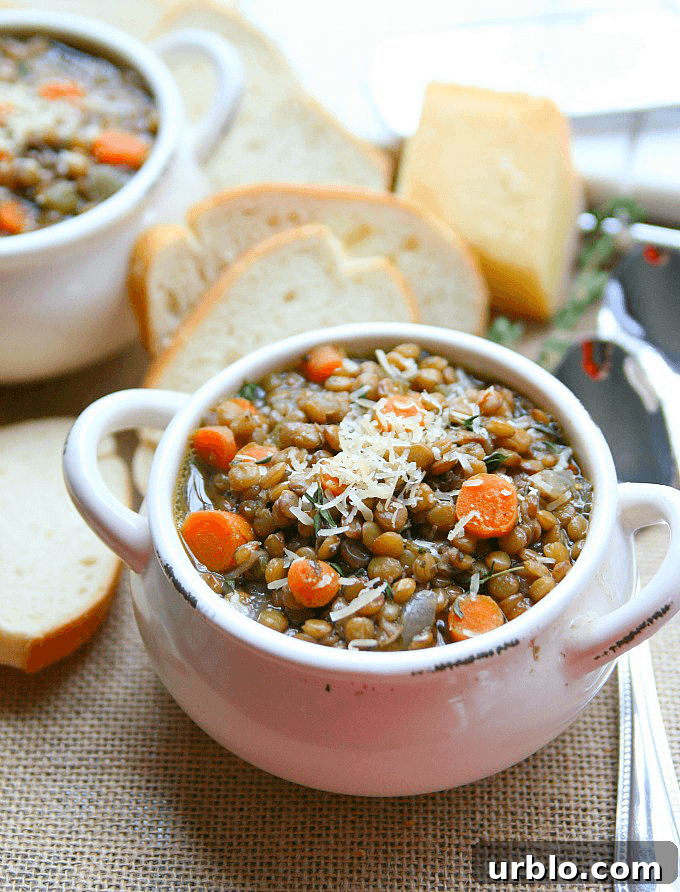 Lentil soup in a bowl with french bread on the side.