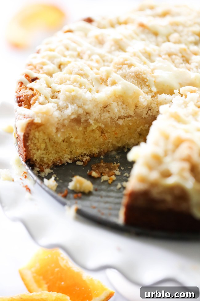 Orange Coffee Cake with a slice removed on a white cake stand.