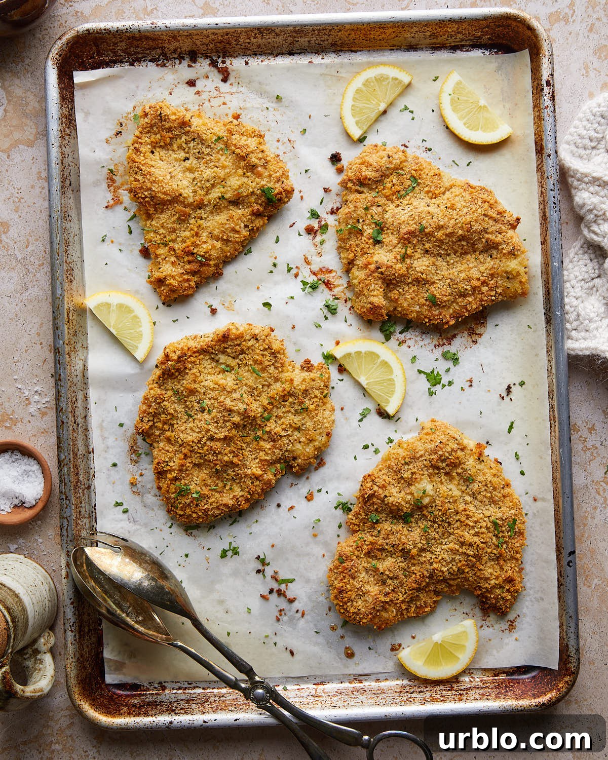 Overhead image of baked chicken cutlets on baking pan. 