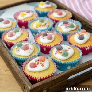 Fairy cakes in a tray decorated in icing sprinkles and sweets
