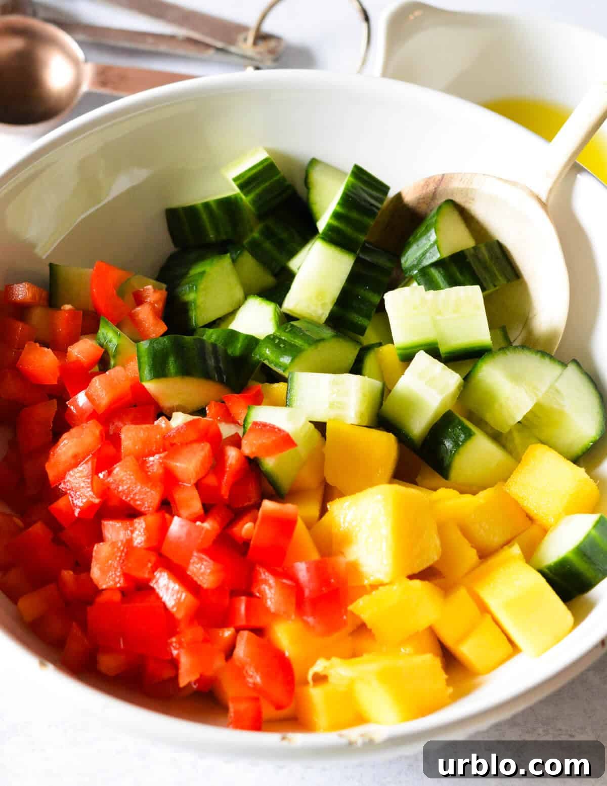 a bowl of chopped cucumber, chopped mango, and diced red bell pepper.