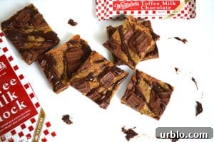 Whittakers Toffee Milk Chocolate Bars. Soft, dense and chewy toffee slice with chocolate chips and Whittakers Toffee Milk Chocolate pieces throughout. Topped with more Whittakers Toffee Milk Chocolate pieces and melted chocolate! Recipe on Lights, Camera, BAKE! #WhittakersToffeeMilkBlock #toffeebars #chocolatetoffeeslice #softtoffeebars #milkchocolatebars