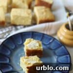 Cornbread with honey and butter on plate.