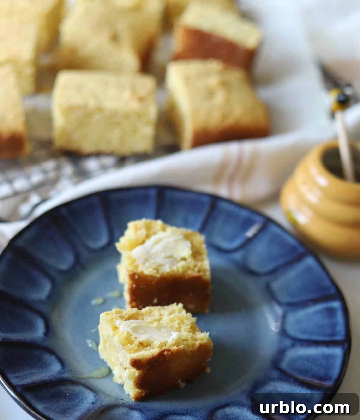 Moist Fluffy Cornbread Recipe Without Buttermilk 8 Cornbread with honey and butter on plate.