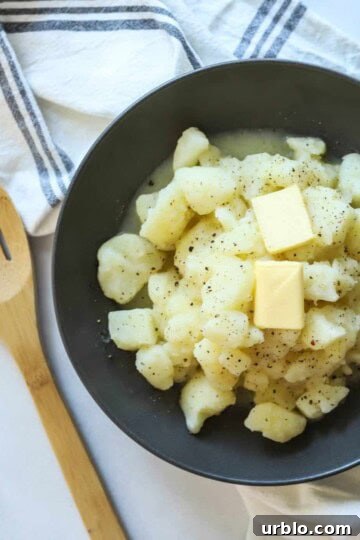 Stewed potatoes in gray bowl with wooden spoon.