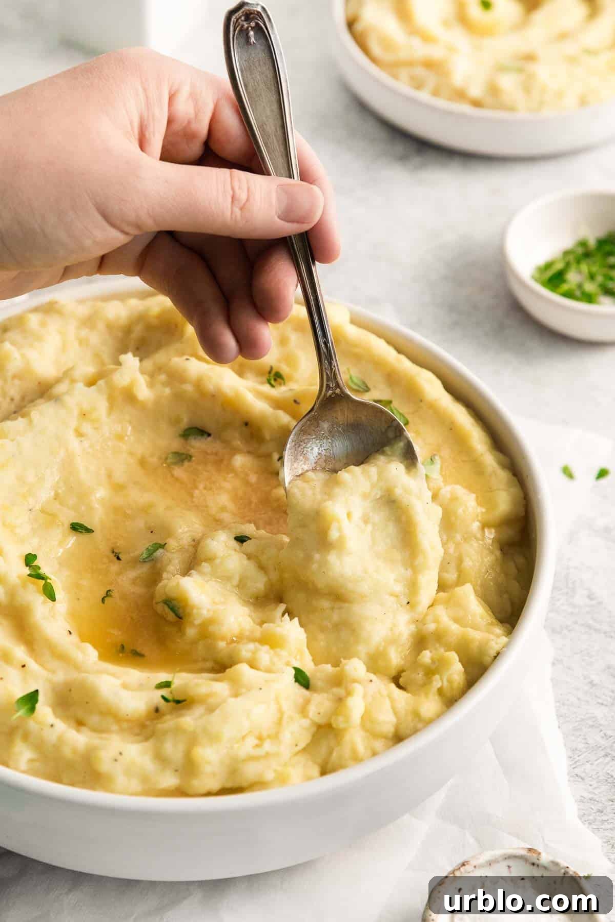 dairy-free potatoes in a serving bowl with a spoon scooping into the bowl.