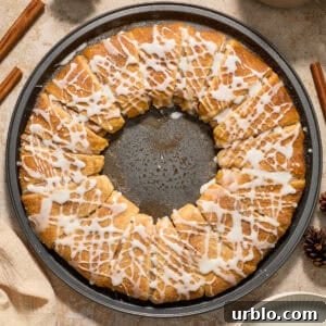 Cinnamon crescent wreath on pan with icing drizzle over top.