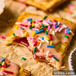 Homemade pop tart with pie crust on parchment with bite taken out.