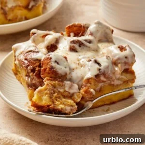 Slice of Brioche French toast bake with cinnamon and cream cheese frosting on plate.