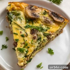 Crustless mushroom quiche with beef, swiss and spinach on white plate and topped with chopped parsley and chives.