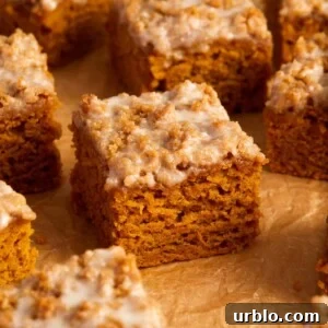 Slices of cinnamon streusel topped pumpkin coffee cake on crinkled brown parchment paper.