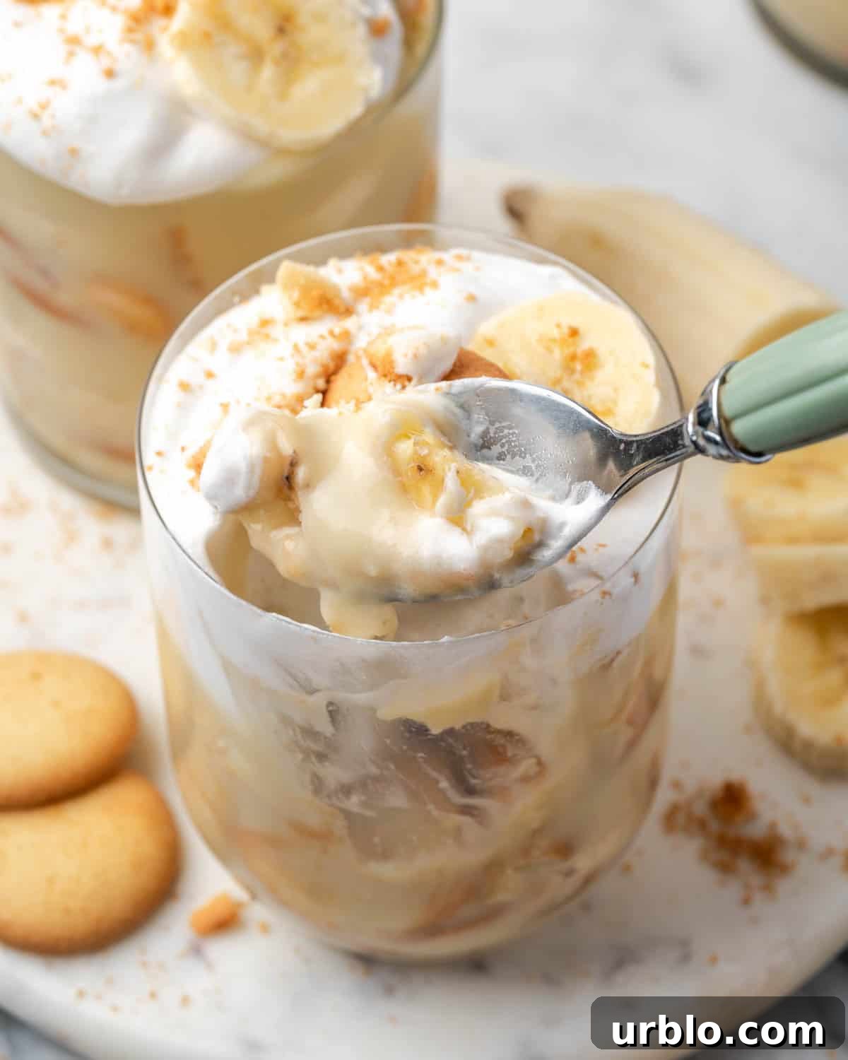 A spoon scooping a bite of banana pudding from a serving glass.