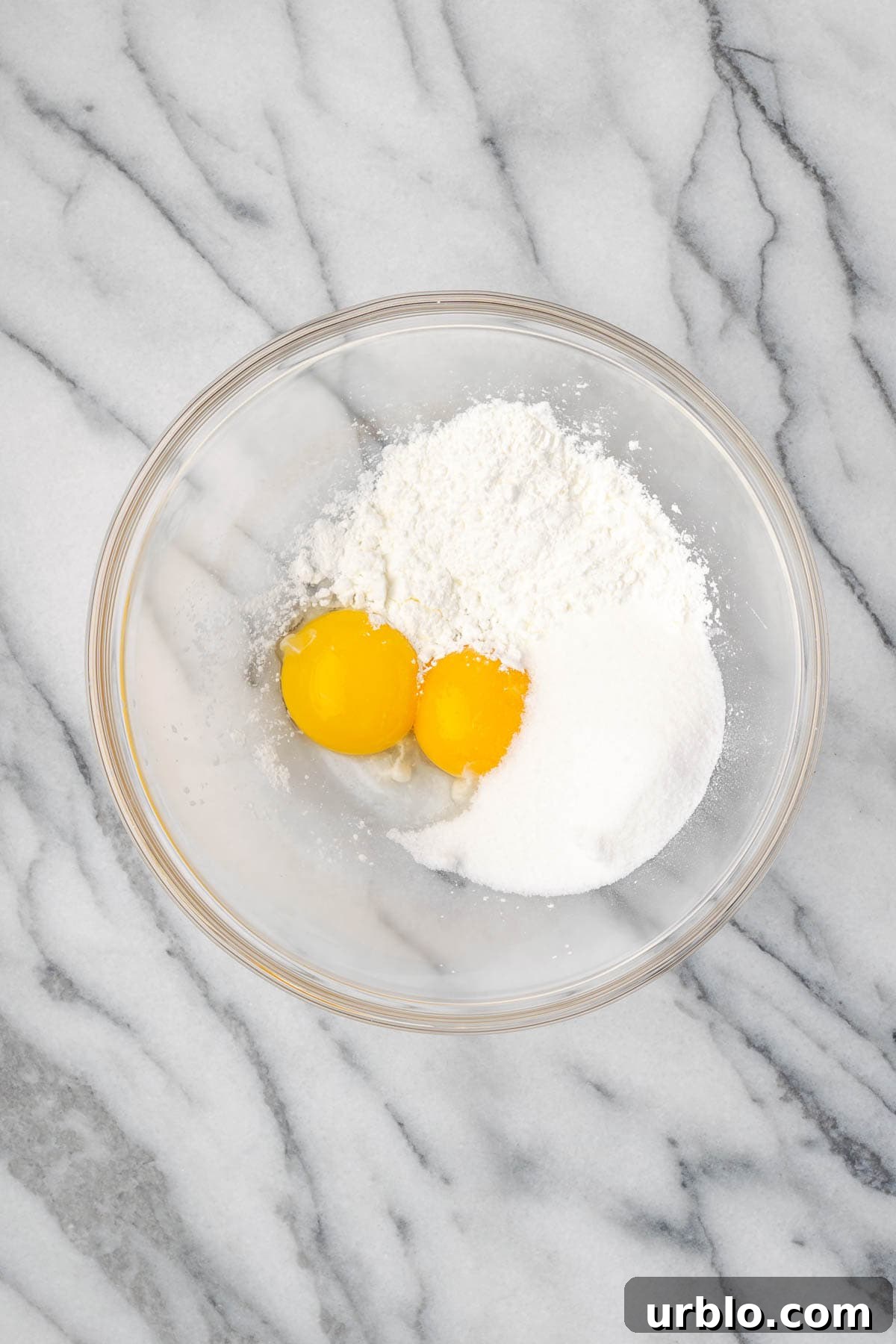 Egg yolks, cornstarch and sugar combined in a large glass mixing bowl. 
