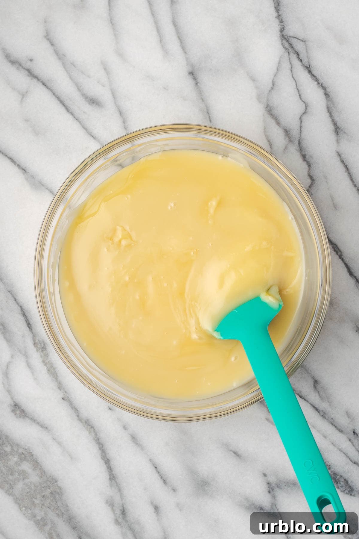 Sweetened condensed milk being stirred into the vanilla pudding. 