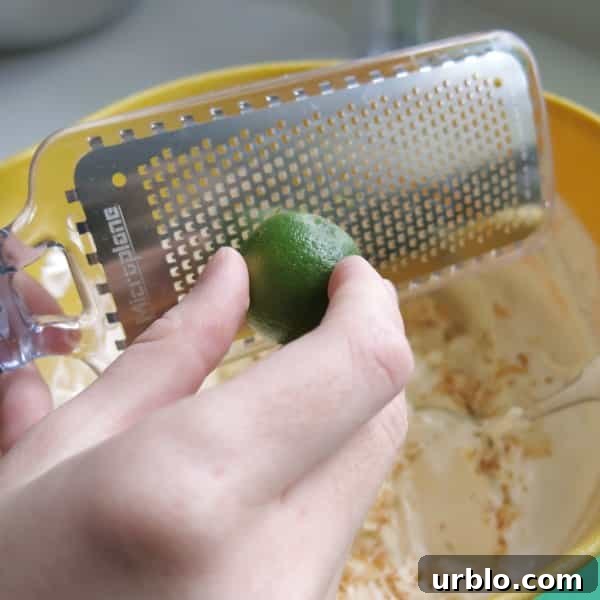 No-Bake Key Lime Pie Dip Recipe 3 A key lime being zested into a large bowl with the rest of the key lime ingredients.