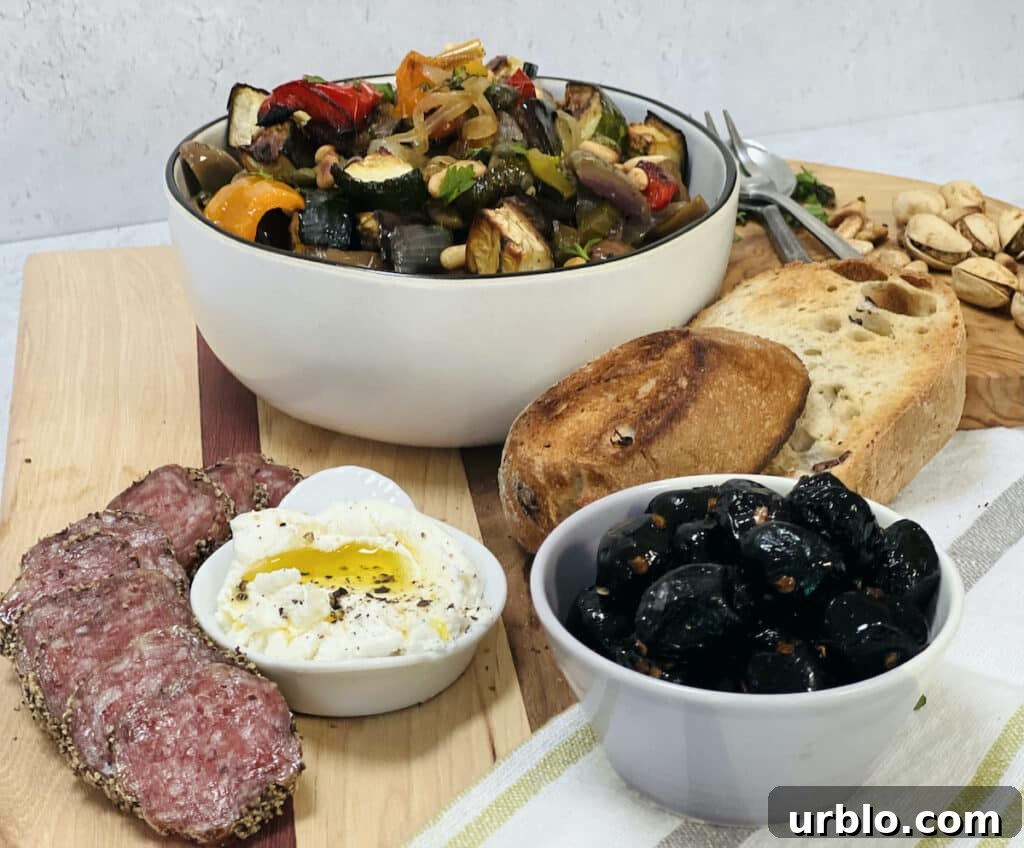Styled photo of vegetable caponata and other antipasto foods (cheeses, salami, olives, bread).