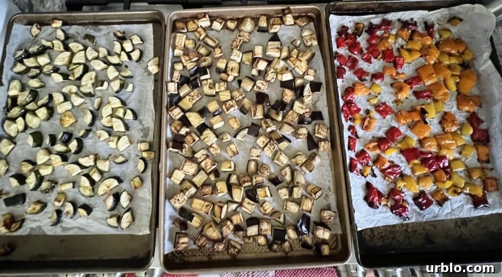 Roasted zucchini, eggplant and bell peppers on separate sheet pans.