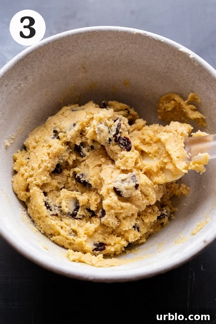 A rubber spatula mixing together biscotti cookie dough in a white ceramic bowl.
