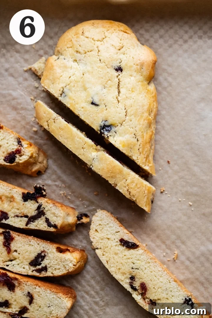 Slices of biscotti biscuits being sliced on parchment paper.