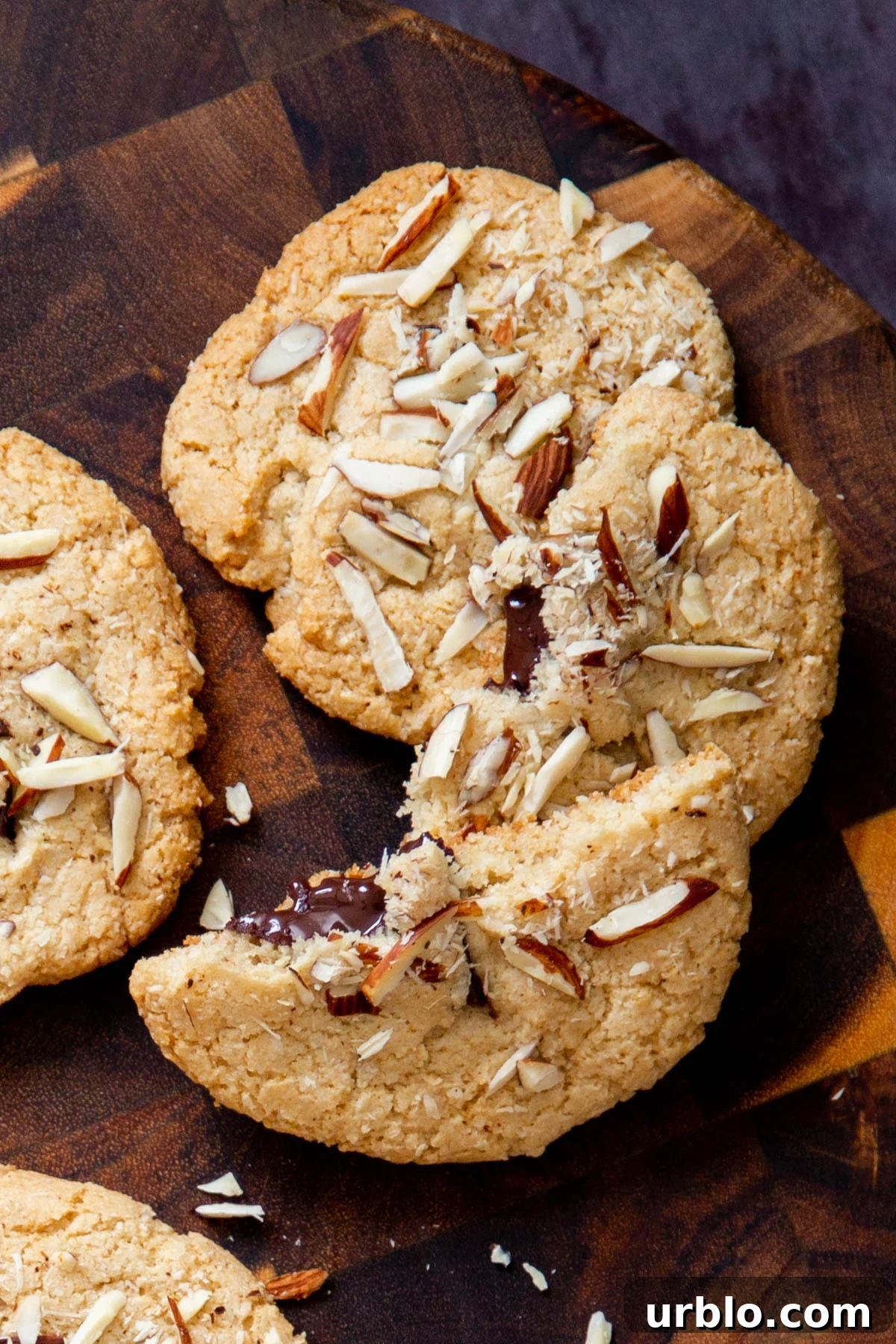 halved vegan almond joy cookies with half melted chocolate chunks peaking out on a wooden board 