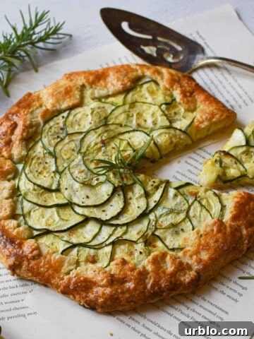Angled view of zucchini ricotta galette with a slice cut out on a white background