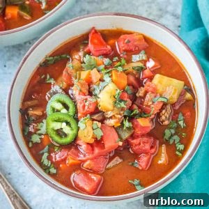 Bowl of veggie chili soup topped with jalapeño slices.