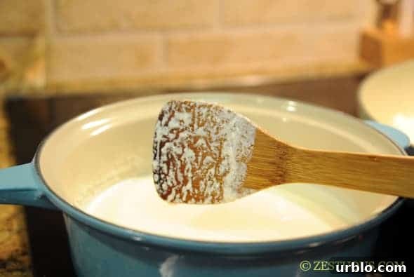 milk boiling in a pot with a wooden spoon