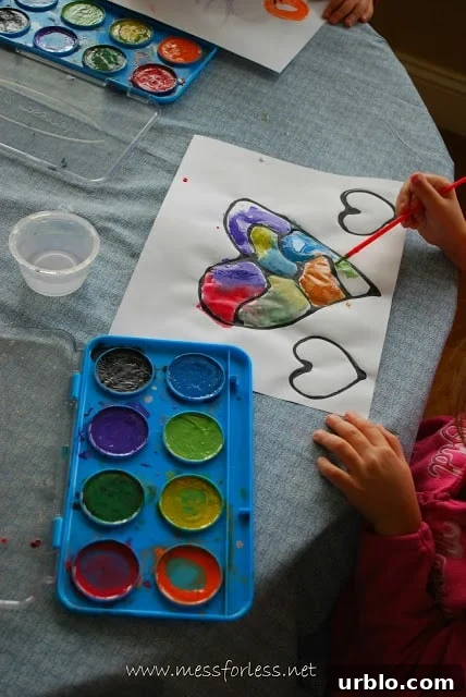 child painting a heart with Black glue using Watercolor paint