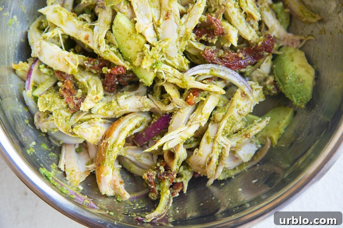 Pesto chicken salad mixed up in a bowl.