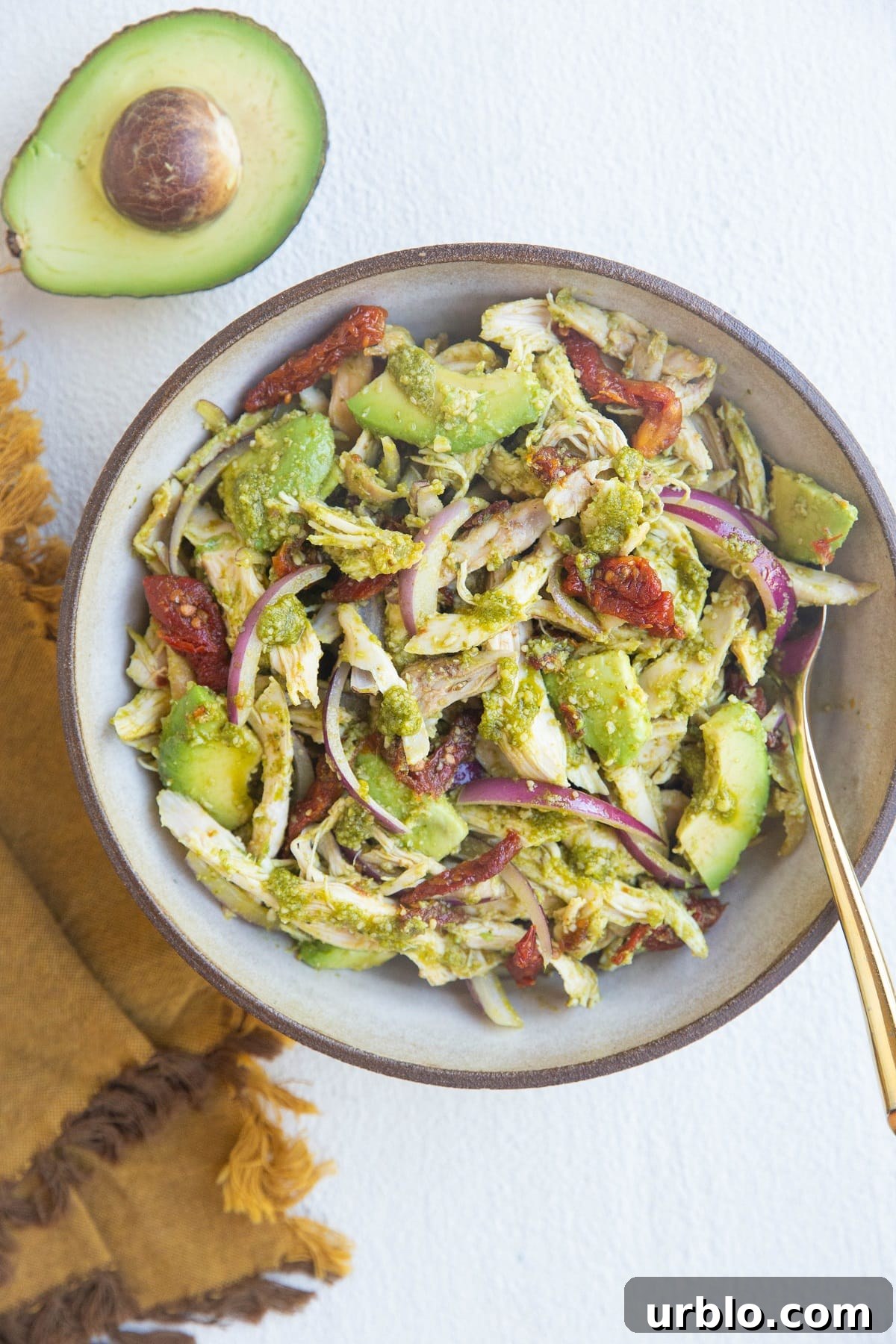 large bowl of chicken salad with avocado and napkin to the side.