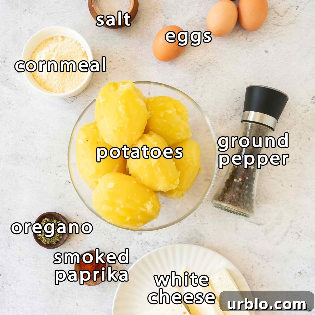 Crispy Potato Fritters Recipe for Golden, Crunchy Hash Browns 3 Overhead shot of ingredients - cornmeal, salt, eggs, potatoes, ground pepper, oregano, smoked paprika, and white cheese.