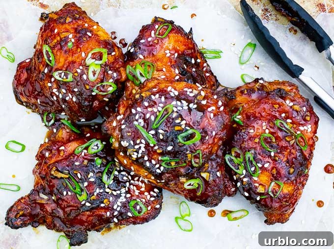 five pieces of Sticky Asian Grilled Chicken Thighs on white background with tongs