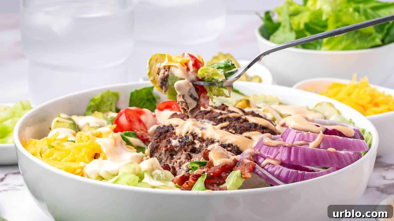 A bowl of salad with sliced red onions, lettuce, tomatoes, shredded cheese, ground beef, bacon, and dressing; a fork holds a bite above the bowl.