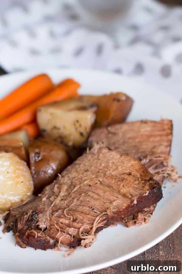 Sliced beef roast with vegetables on white plate.
