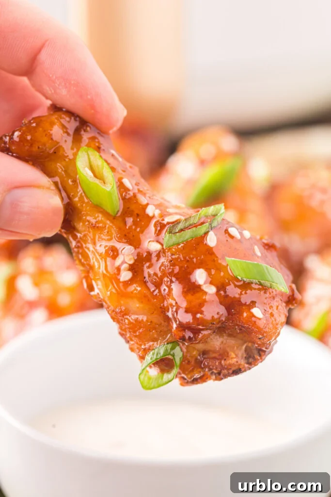 hand getting ready to dip honey sriracha wings in dip