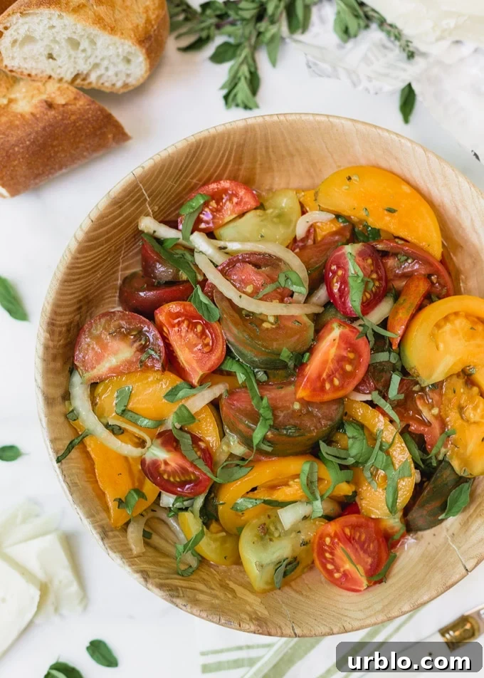 heirloom tomato salad with onions and basil in a wooden bowl
