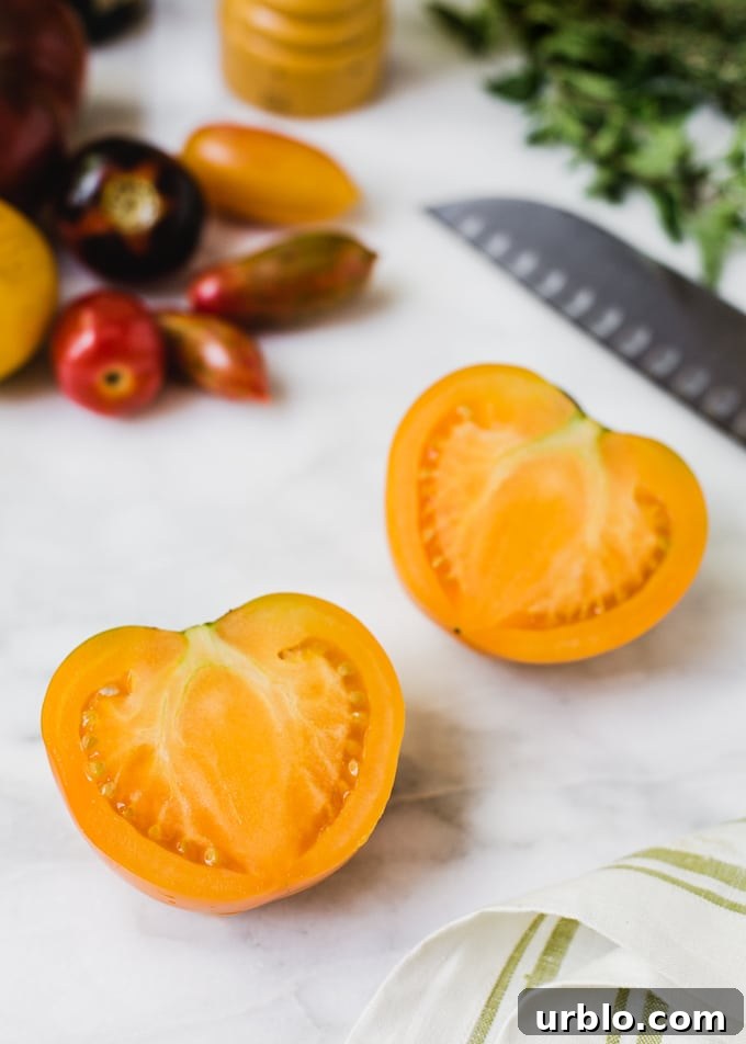 halved orange tomato on a marble board with a santoku knife