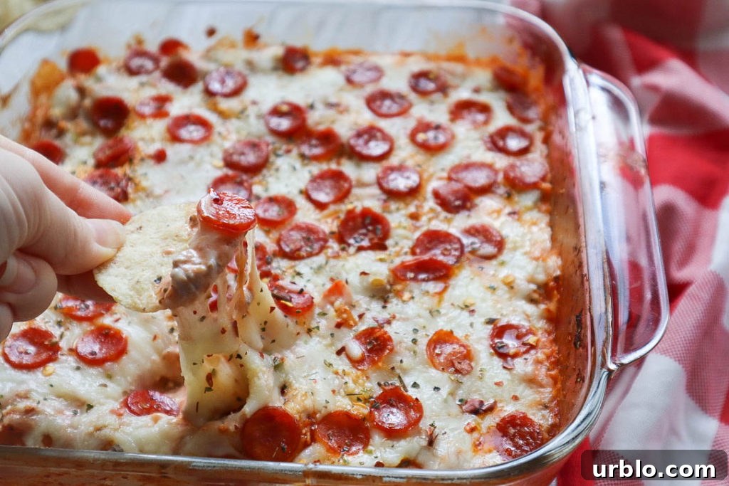glass baking dish with pizza dip topped with melted cheese and mini pepperoni.