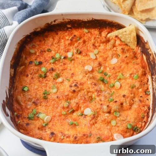 white baking dish with chip in the buffalo dip topped with green onion