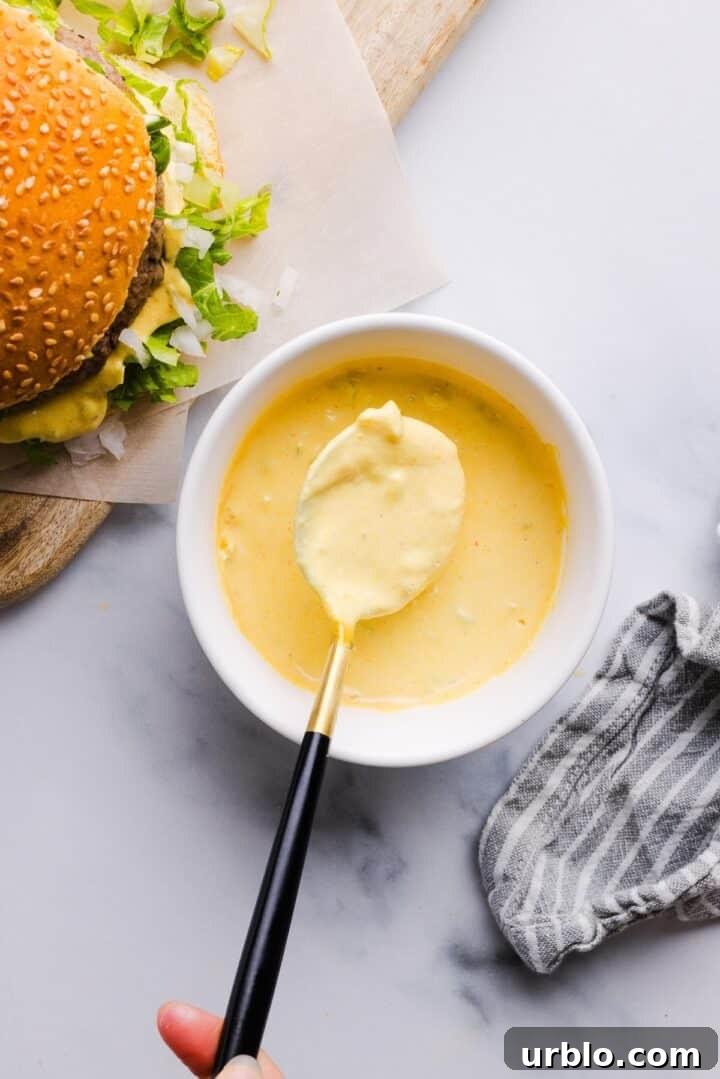 Overhead photo of burger sauce in a small white bowl, near a burger