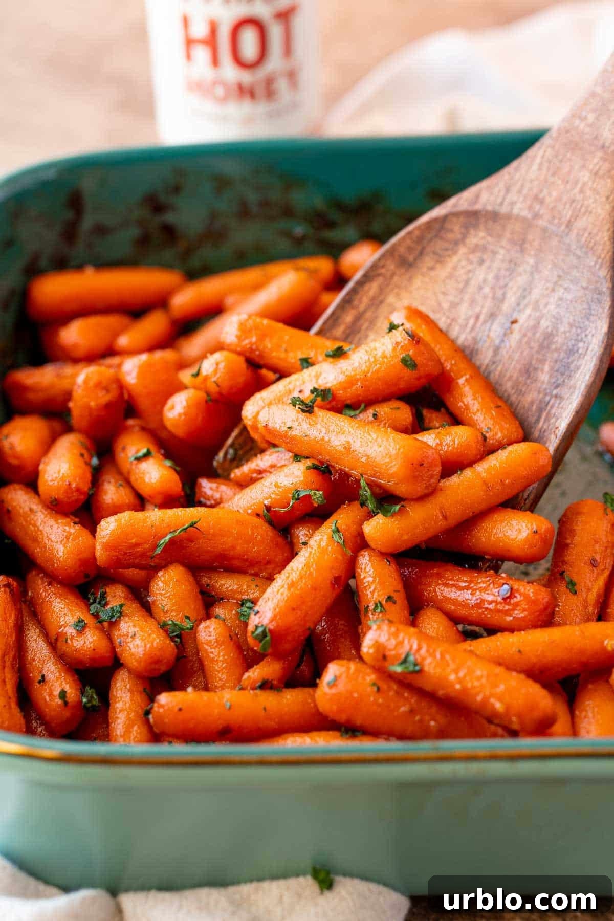 Spicy Honey-Glazed Carrots with Brown Butter and Herbs 5 A serving spoon scooping hot honey glazed carrots out of a baking dish.